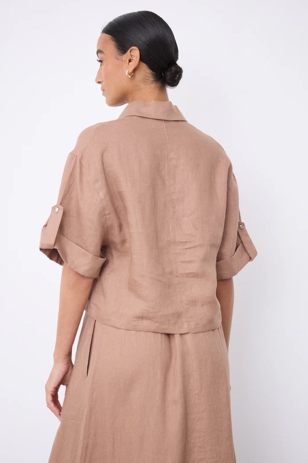 Vue de dos de la blouse courte en lin à col ouvert, manches revers et tissu léger, idéale pour la saison chaude.