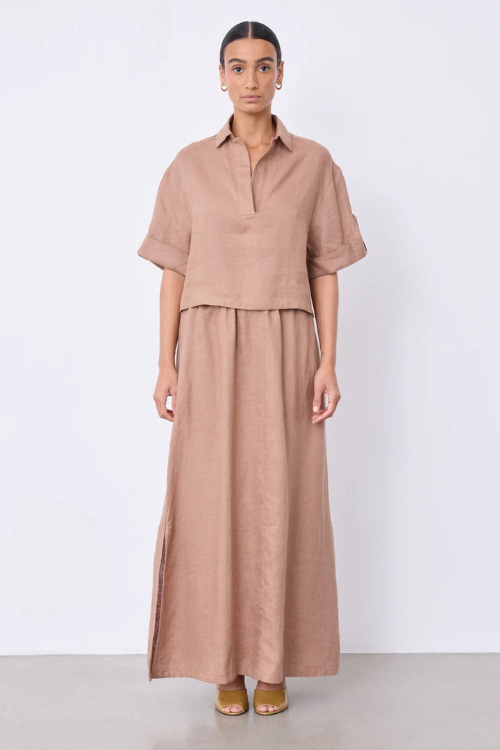 Femme portant une blouse courte en lin à col ouvert avec manche courte et col en V, idéale pour un style décontracté et élégant.