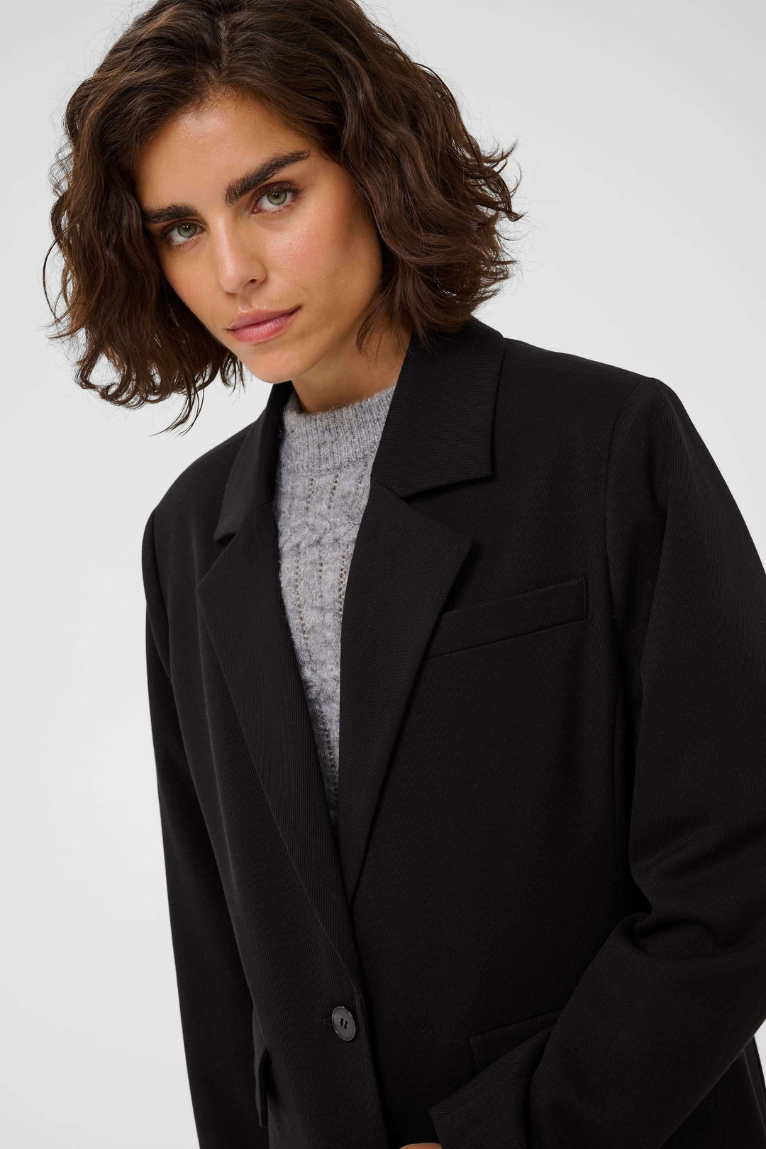 Femme portant le Manteau Milos, coupe droite et élégante, en noir. Parfait pour un style raffiné et polyvalent au quotidien.