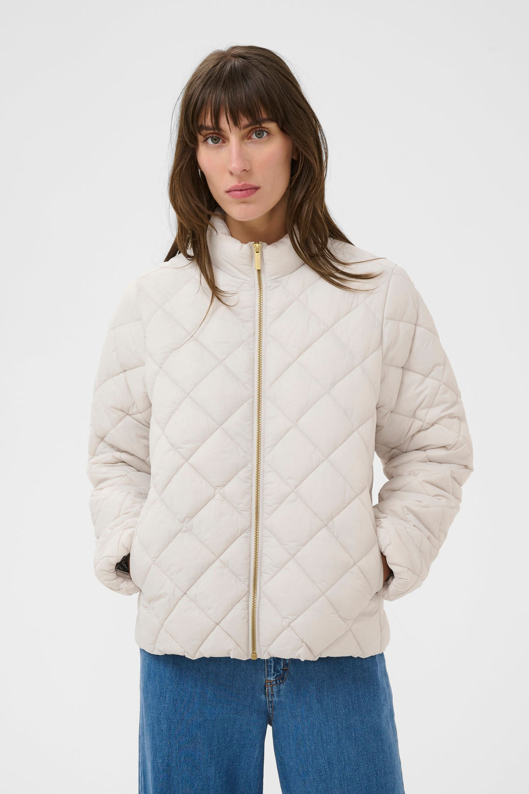 Femme portant le Manteau Olia matelassé beige, coupe droite, col montant, fermeture éclair, style moderne et fonctionnel.