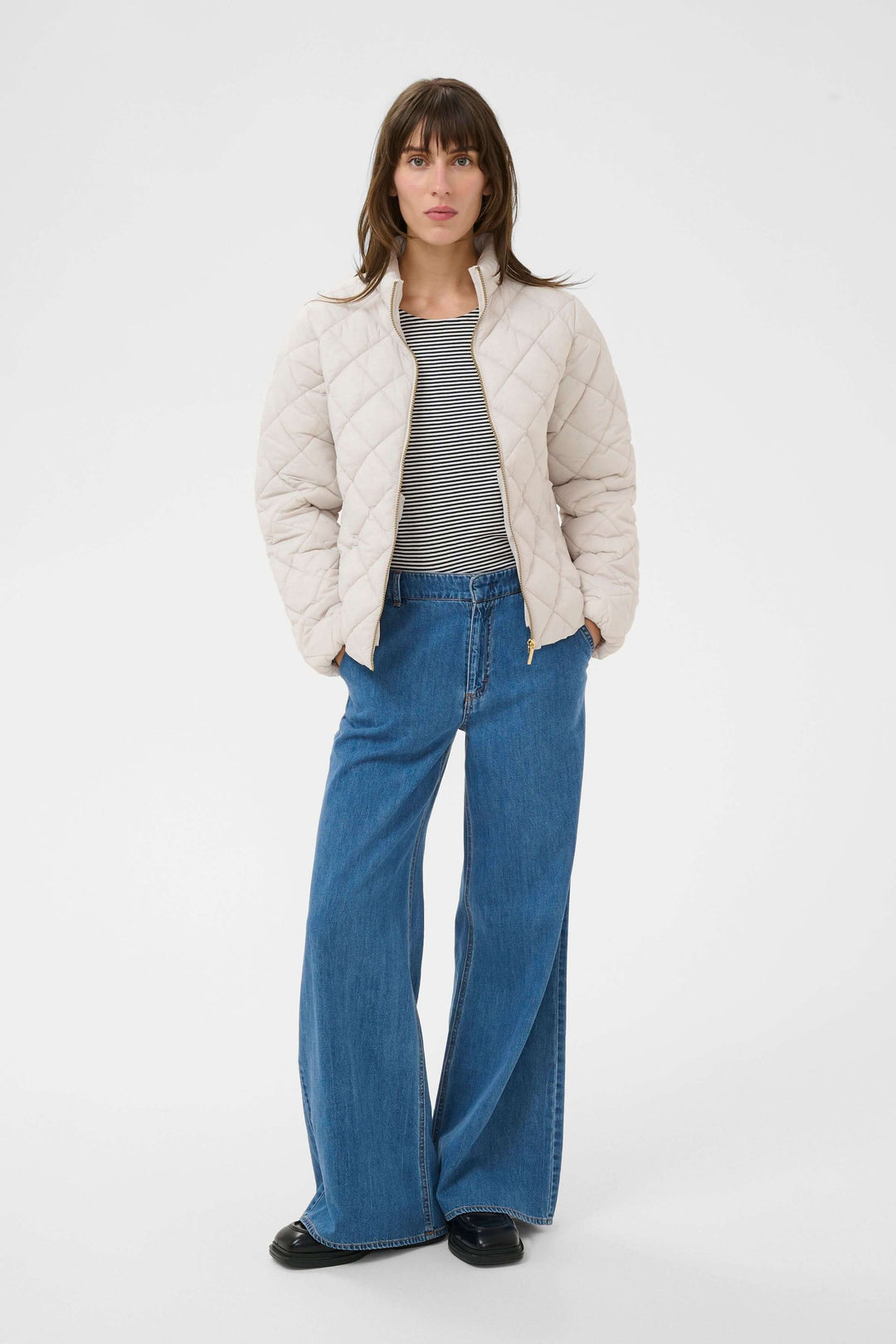 Femme portant le Manteau Olia matelassé, coupe droite, col montant, avec un style épuré et moderne pour temps frais.