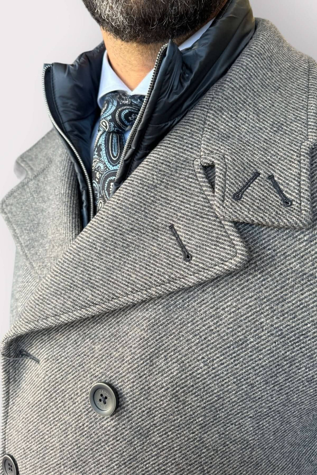 Manteau caban doublé élégant avec col montant et boutons, porté avec une cravate stylée.