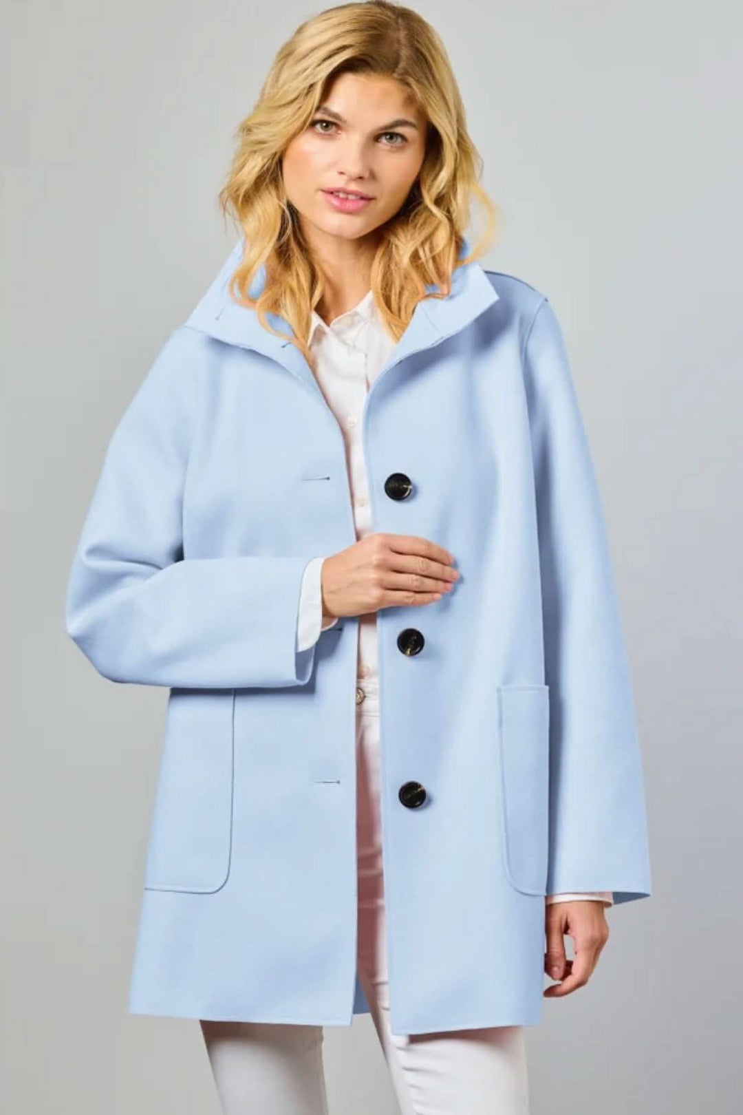 Femme portant le Manteau de style Nanna, élégant et intemporel, bleu clair avec fermeture boutonnée, idéal pour la mi-saison.
