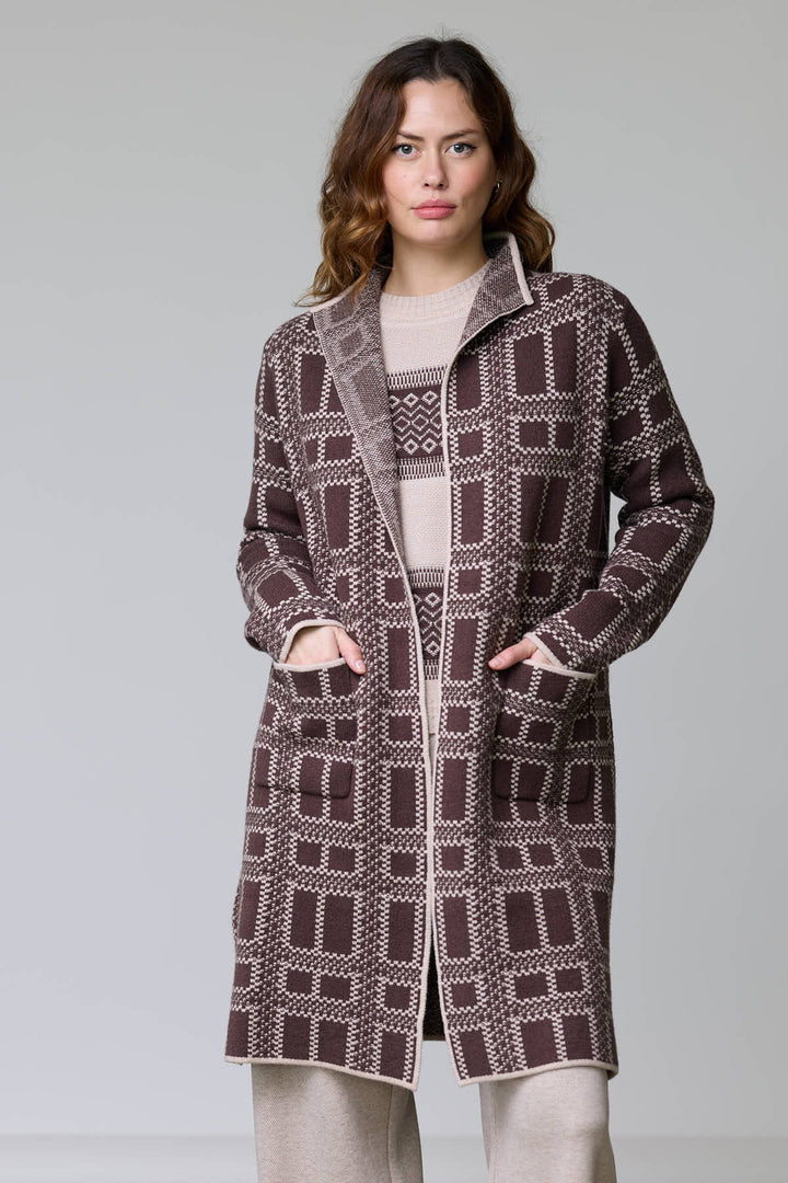 Femme portant un manteau en tricot à motif géométrique avec col ouvert et poches plaquées, coupe droite et finitions contrastantes.