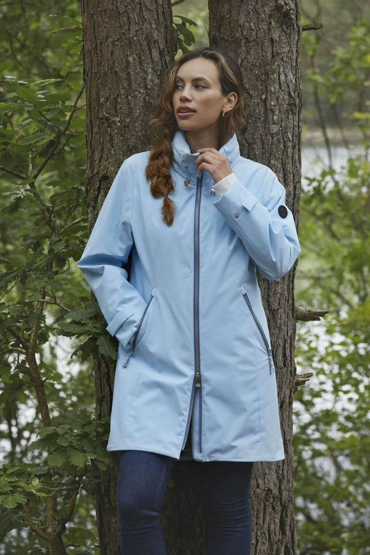 Manteau long à capuchon bleu clair, coupe droite, porté par une femme, en pleine nature.