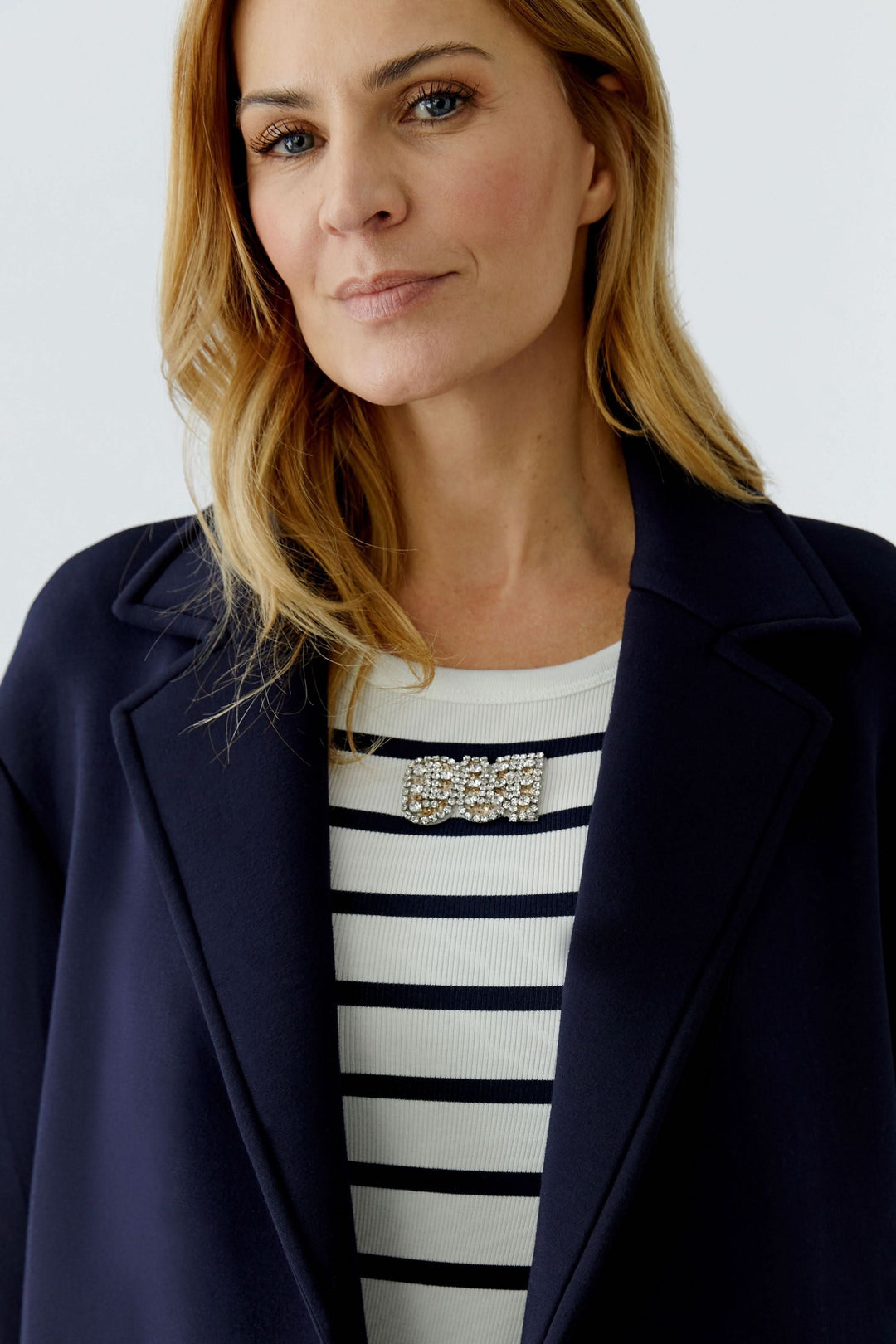 Femme portant un manteau long à coupe droite avec col tailleur classique, idéal pour une silhouette élégante et structurée.