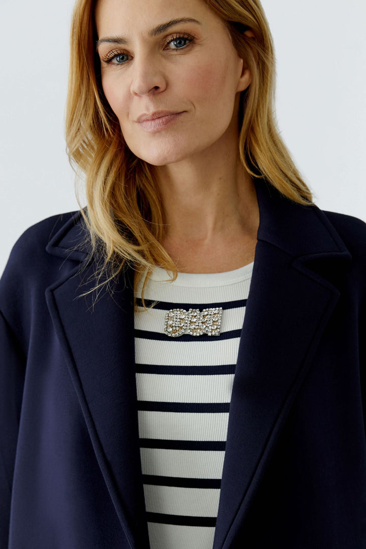 Femme portant un manteau long à coupe droite avec col tailleur classique, idéal pour une silhouette élégante et structurée.