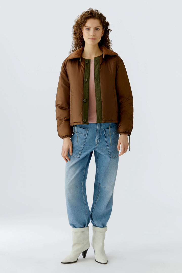 Femme portant un manteau réversible matelassé avec jeans et bottines blanches, montrant deux styles en une pièce.