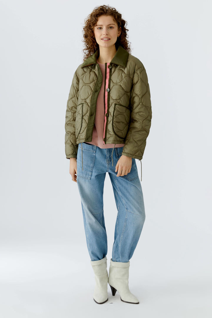 Femme portant un manteau réversible matelassé kaki, style moderne et épuré pour les transitions de saison.