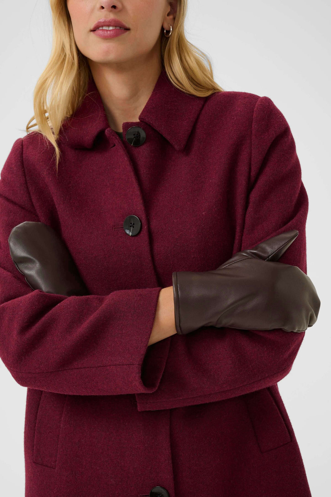 Femme portant un manteau bordeaux avec des mitaines en cuir marron, décorative et élégante pour l'hiver.