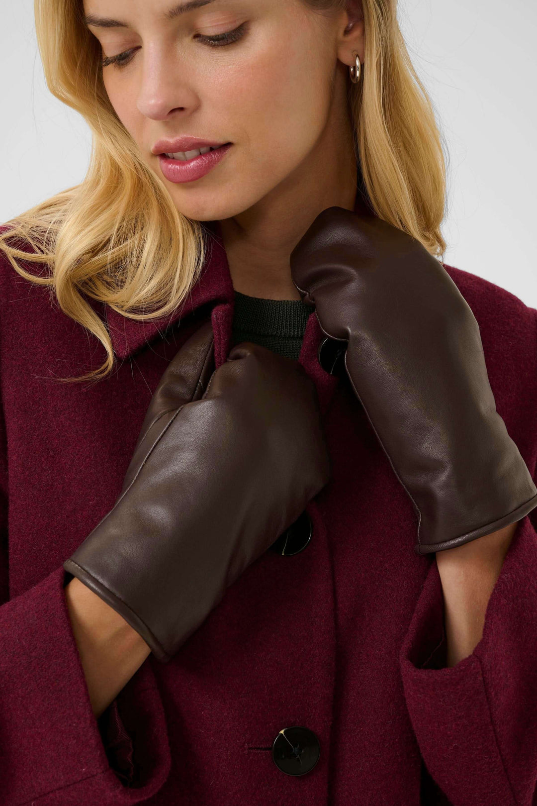 Femme portant des mitaines en cuir Fiori marron avec manteau bordeaux, parfaites pour l'hiver.