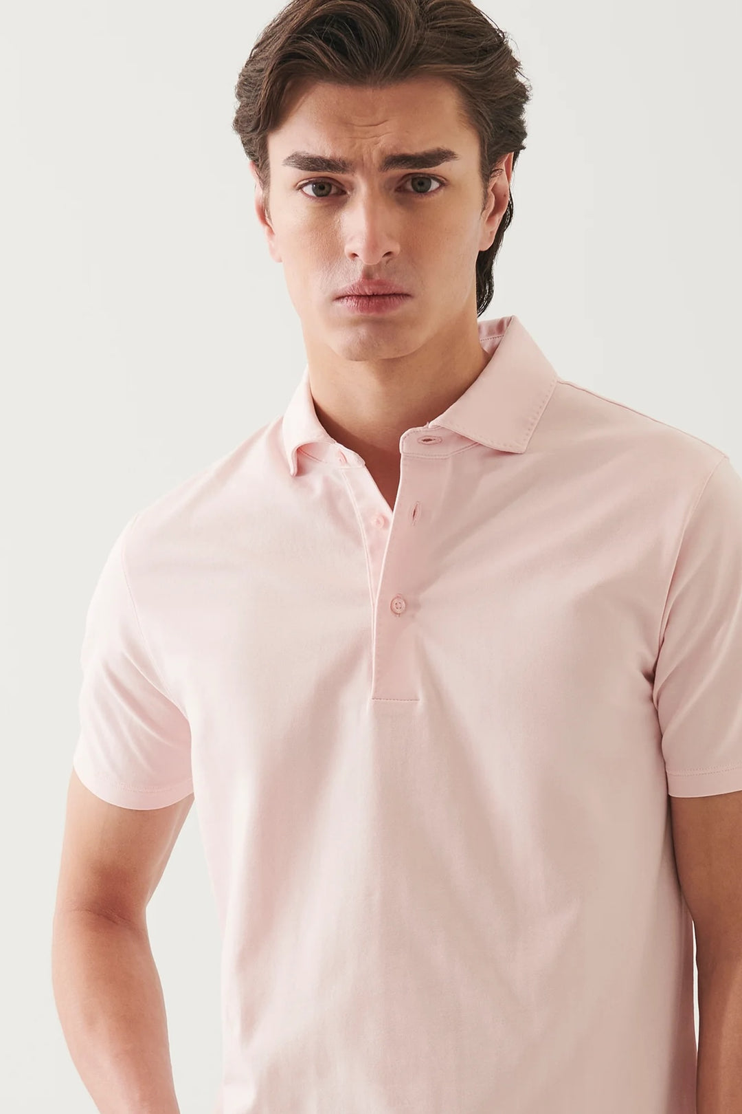 Homme en polo manches courtes rose, au design minimaliste et confort doux, parfait pour l'été.