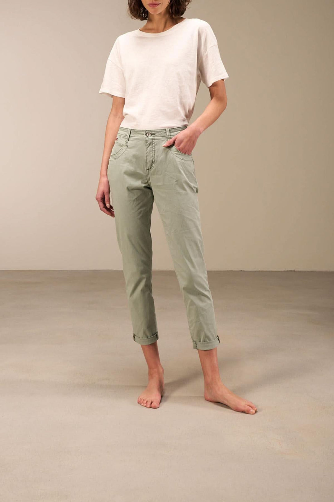 Pantalon 7/8 moulant à taille basse en coton bio, avec ourlet retroussé et bandes décoratives, couleur vert pâle.