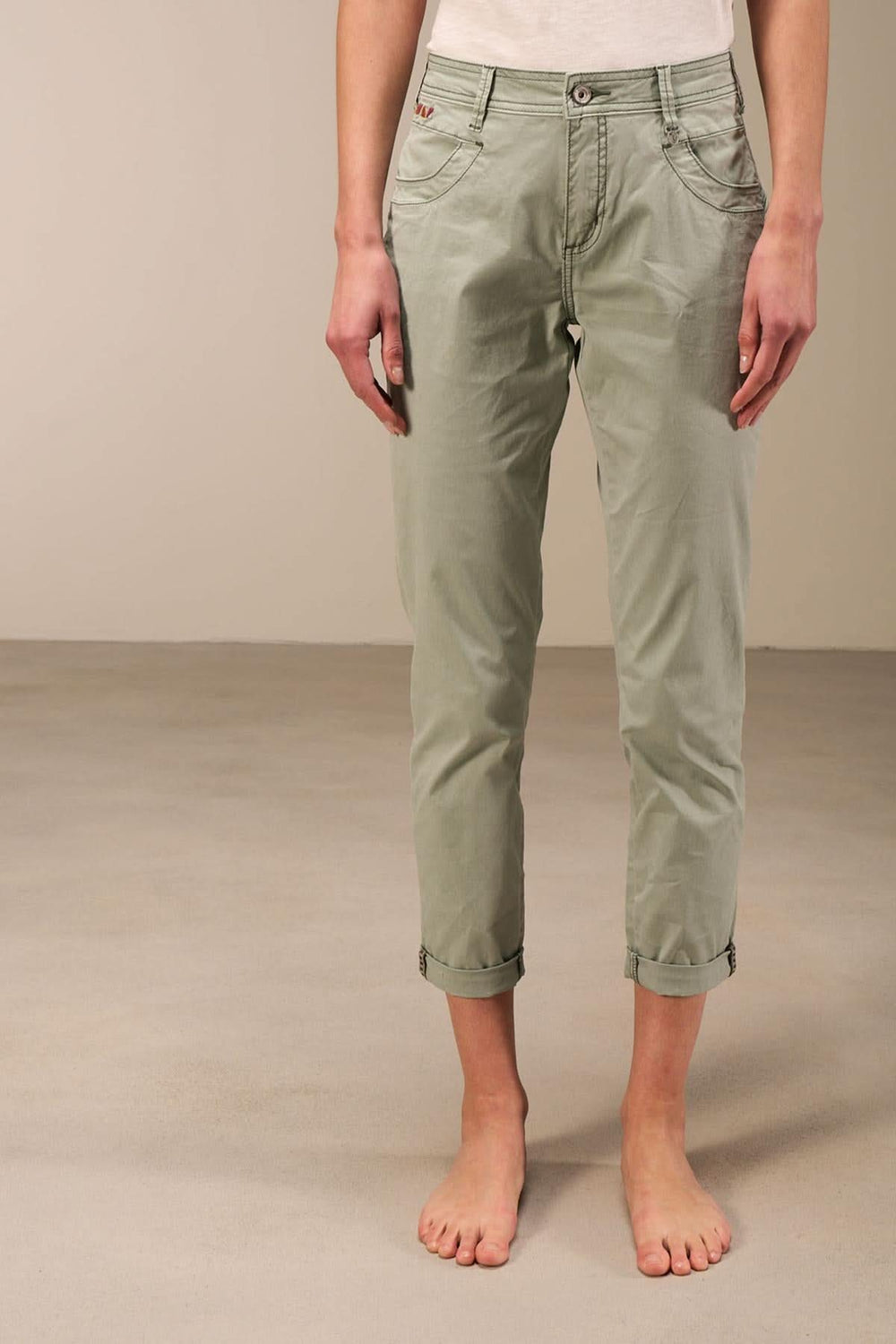 Pantalon 7/8 moulant à taille basse, couleur vert, avec ourlet retroussé et design moderne à 5 poches.