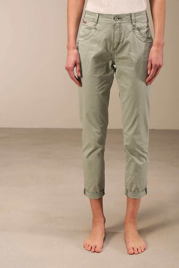Pantalon 7/8 moulant à taille basse, couleur vert, avec ourlet retroussé et design moderne à 5 poches.