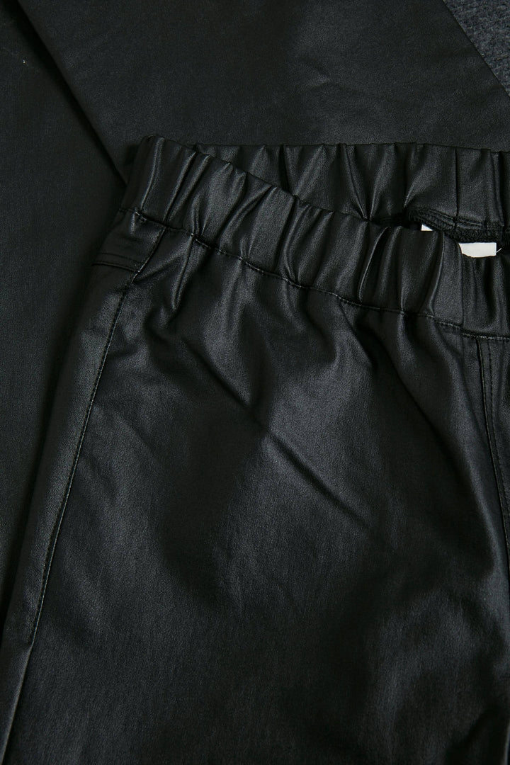 Détails du pantalon Ada en simili cuir noir avec une taille élastique pour un look moderne et sophistiqué.