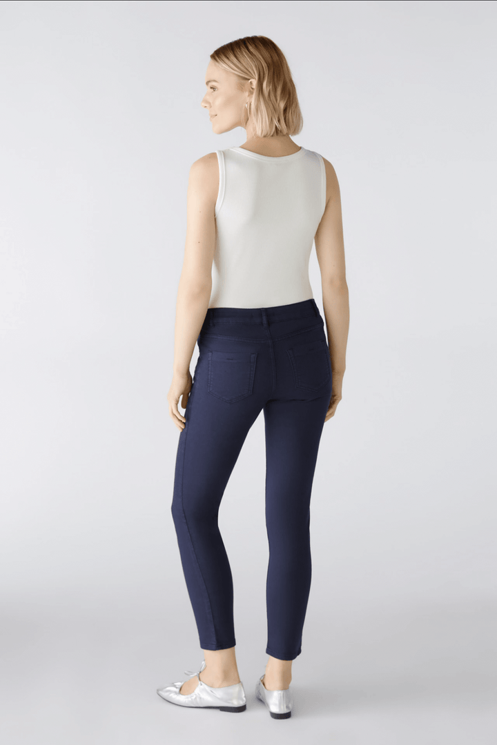 Femme portant un pantalon Baxtor slim en bleu marine, vu de dos, associé à un débardeur blanc.