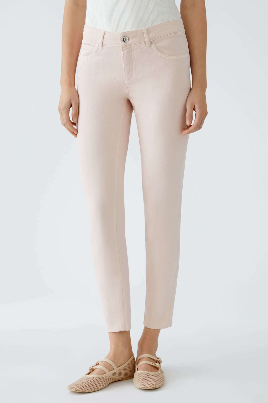 Pantalon Baxtor slim rose à taille mi-haute, longueur raccourcie, porté avec des chaussures confortables.