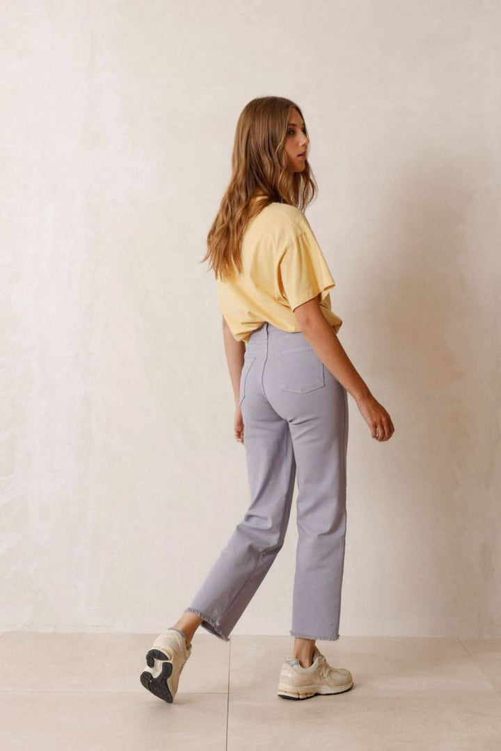 Femme avec un t-shirt jaune et un pantalon court bleu associé à des baskets, affichant un look décontracté et moderne.