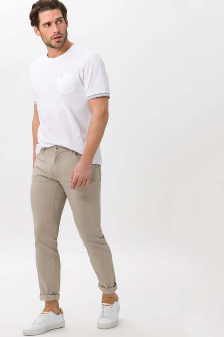 Homme portant un pantalon Hi-Flex beige avec un t-shirt blanc, style décontracté et moderne.