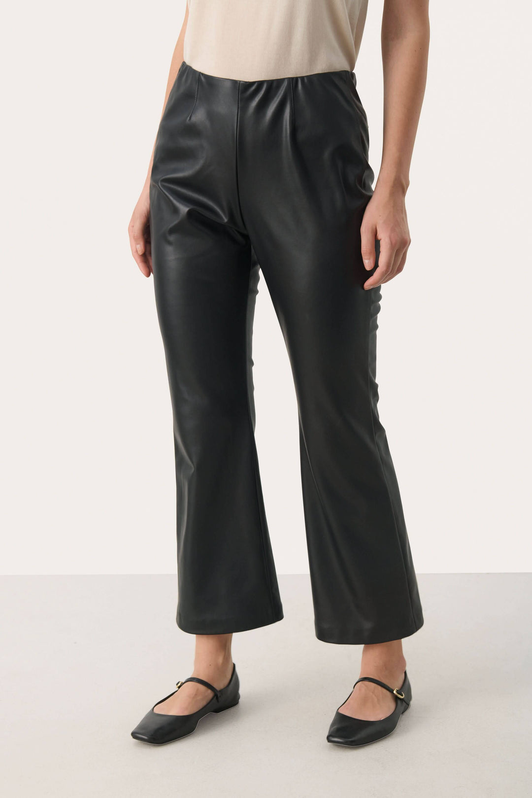 Pantalon Lorenza noir en simili cuir, taille haute élastiquée, coupe légèrement évasée, style moderne et urbain.