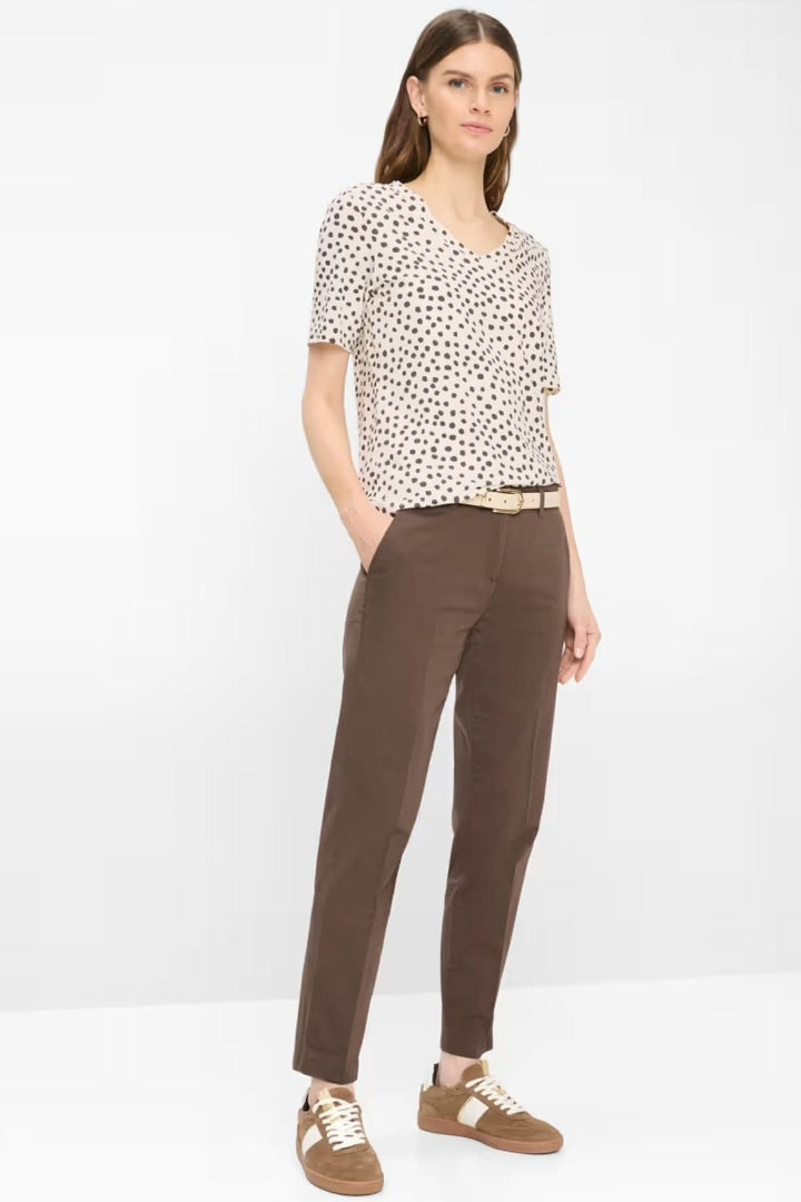 Femme portant un Pantalon Maron coupe droite en tissu extensible, longueur cheville, avec poches latérales et arrière, style moderne.