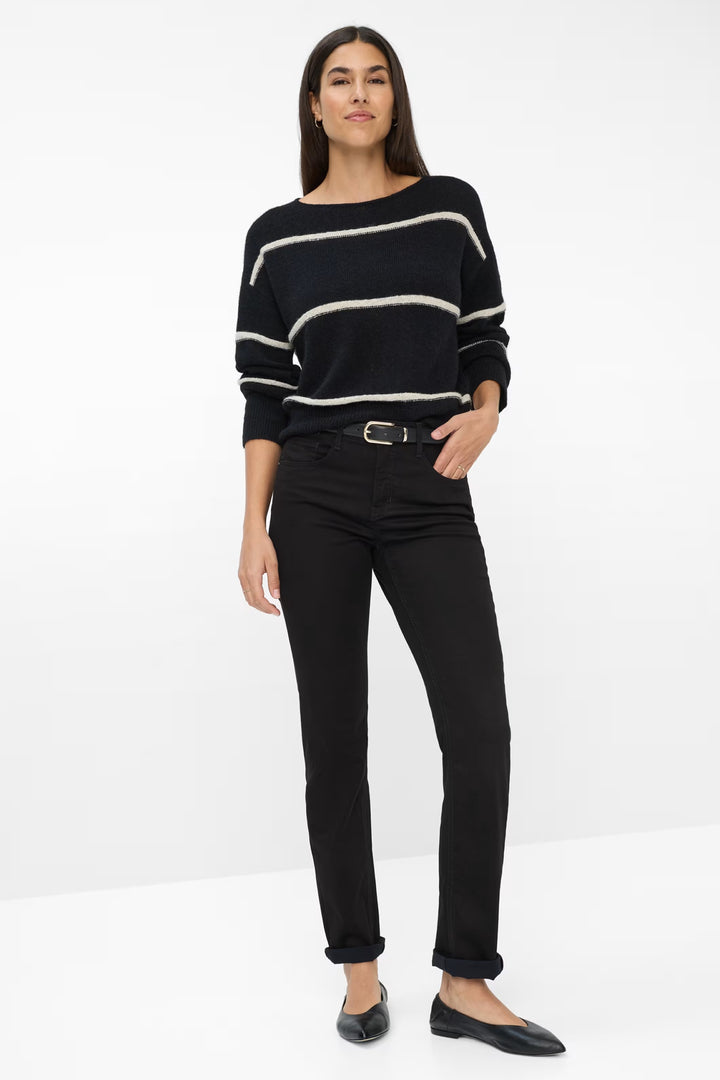 Femme portant un chandail rayé noir et blanc avec un pantalon noir classique pour un look élégant et décontracté.