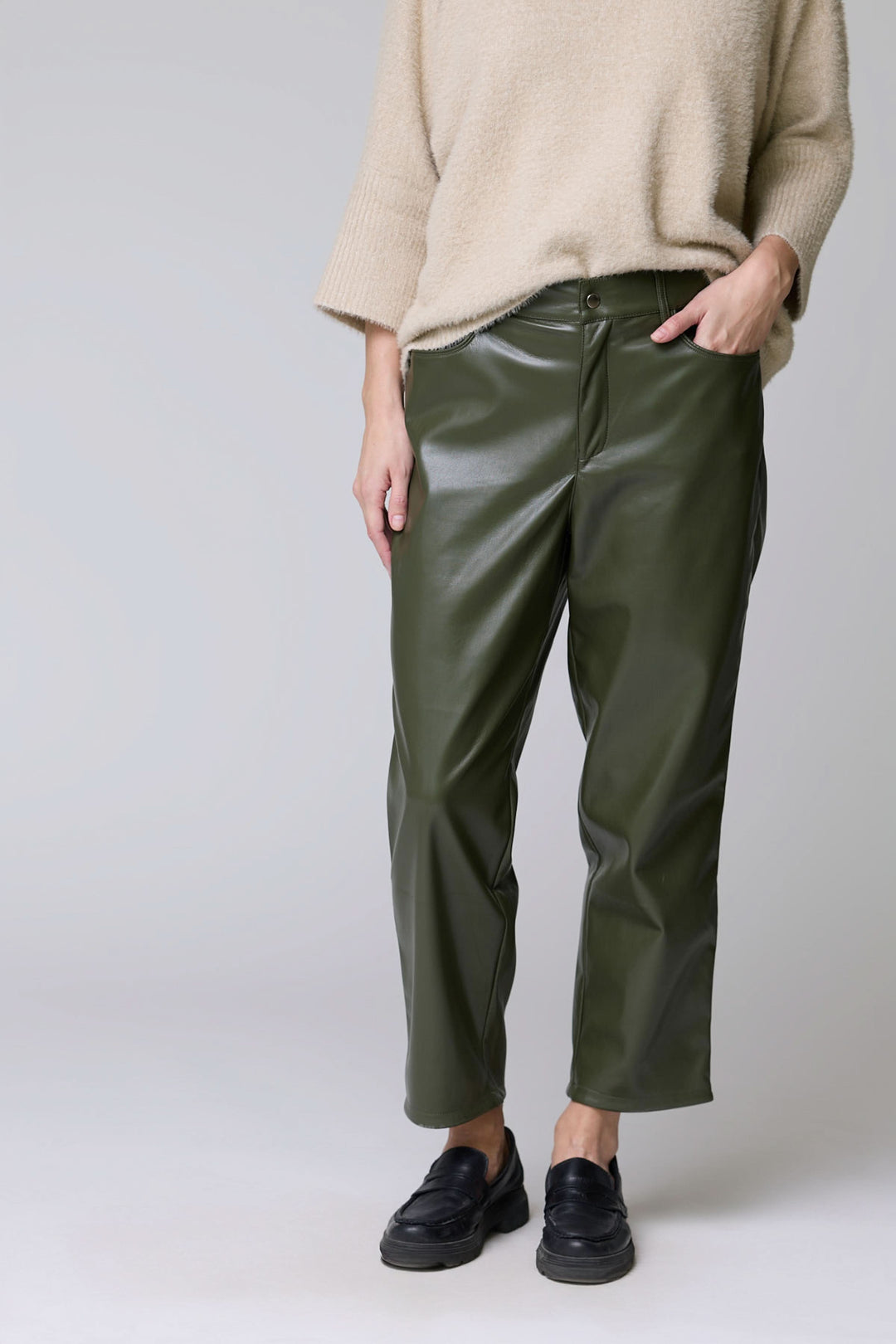 Pantalon Sabrna effet cuir vert avec coupe droite et finition satinée, porté avec un pull beige, offrant un look urbain chic.
