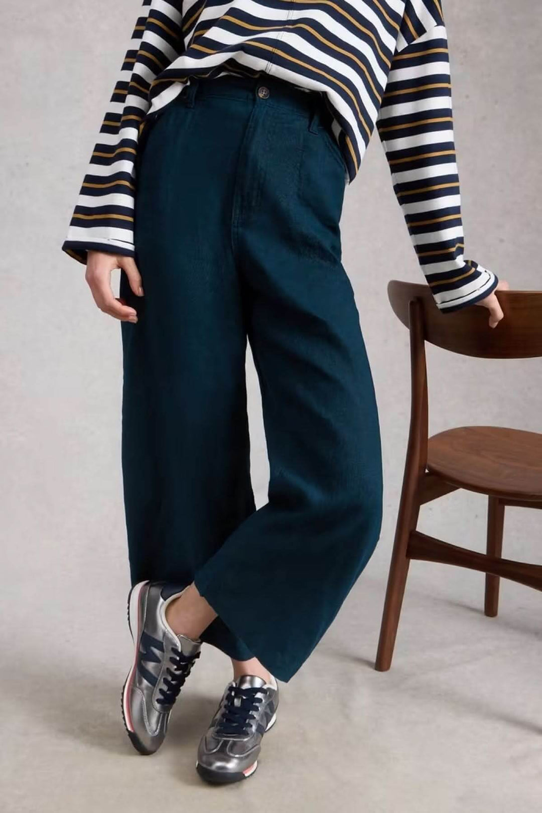 Personne portant un Pantalon Tia à jambes larges avec une blouse rayée et des baskets, posture décontractée près d&
