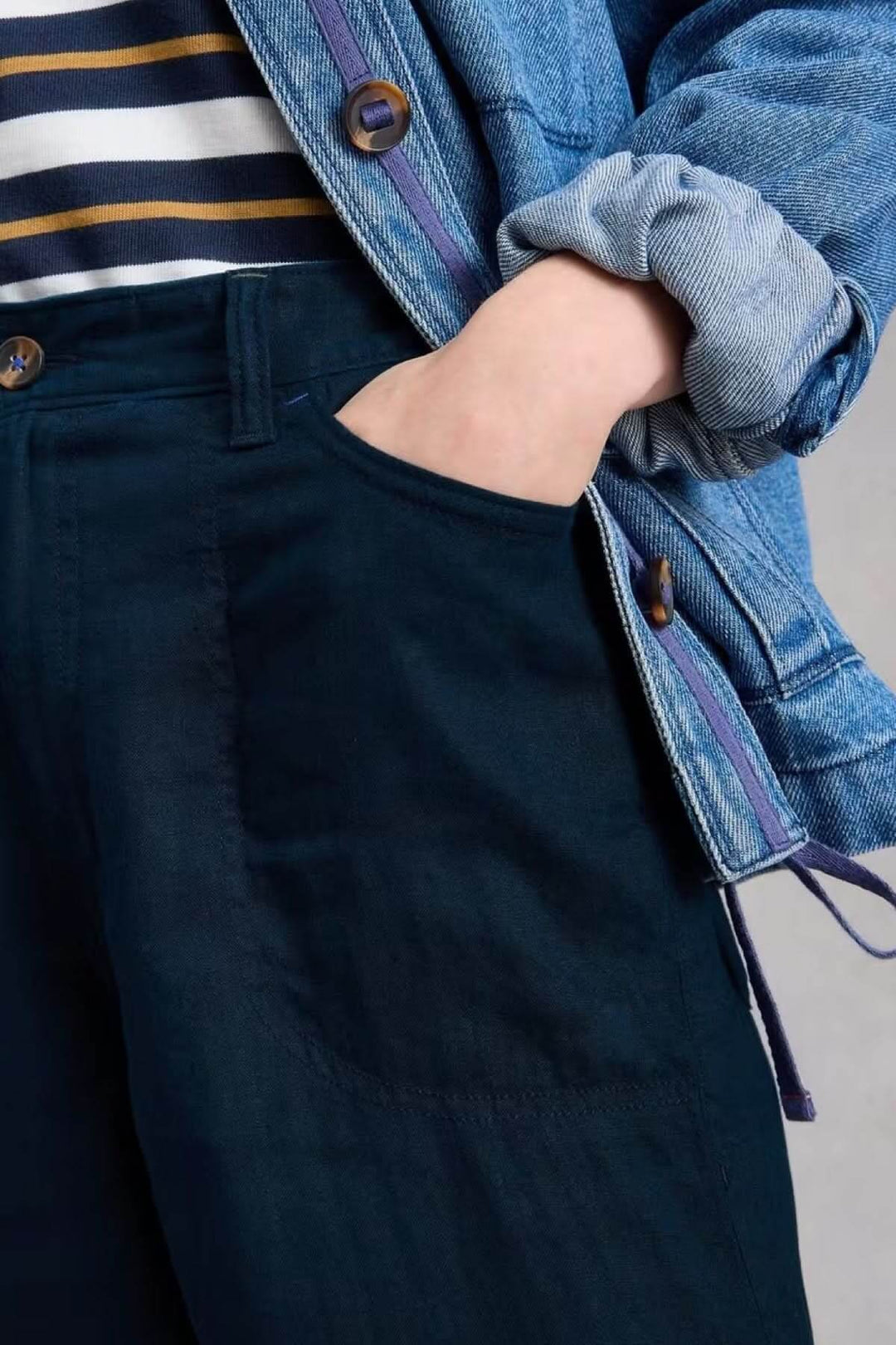 Person wearing Pantalon Tia à jambes larges with pocket detail and casual outfit including denim jacket.