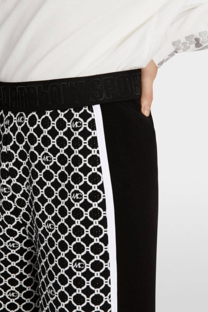 Détail du pantalon WUSU avec motif chaîne en tricot et ceinture élastique noire.