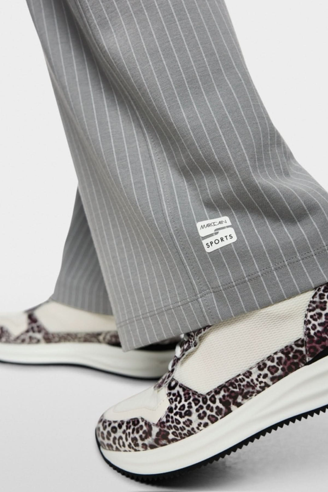 Gros plan sur le bas du Pantalon Washington à rayures grises avec des baskets imprimées léopard.