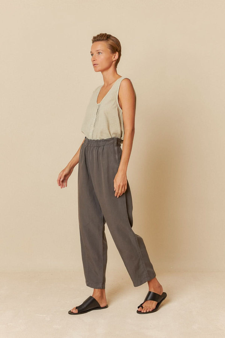 Femme portant un pantalon ample gris avec taille élastiquée et haut léger, style chic et décontracté.
