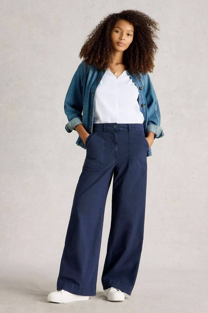 Pantalon ample à la taille haute, coupe large et élégante, associé à une chemise blanche et un jean bleu.