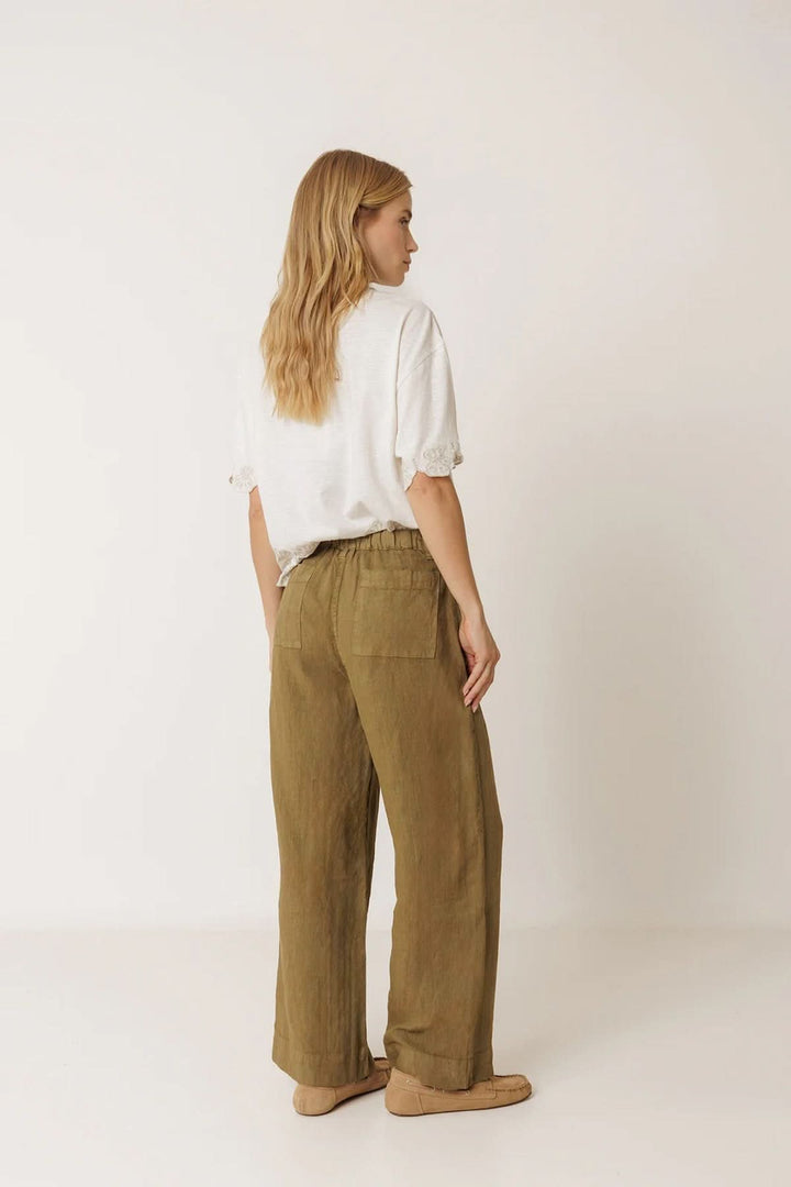 Femme portant un pantalon ample en lin à poches plaquées avec une coupe évasée, offrant un look décontracté et naturel.