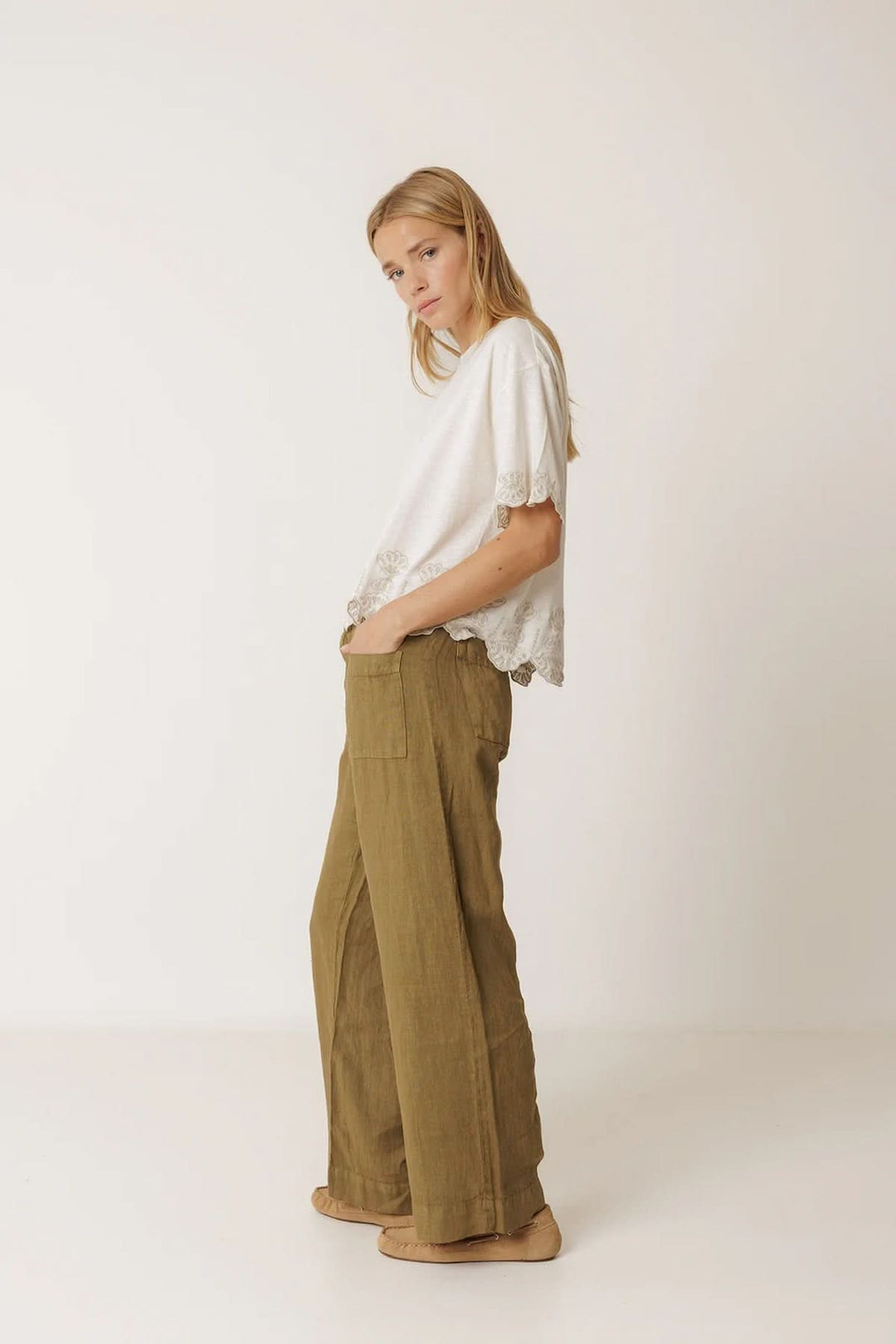 Femme portant un pantalon ample en lin à poches plaquées, décontracté et moderne, avec un t-shirt blanc de style fluide.