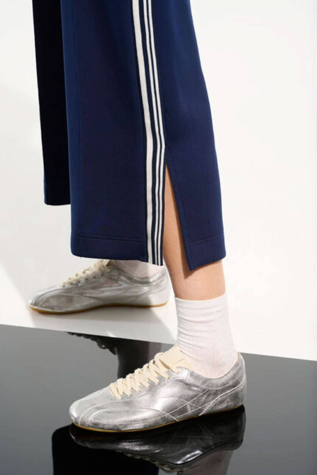 Pantalon athlétique à bandes contrastantes avec fente latérale et bandes verticales pour un look sportif chic et moderne.