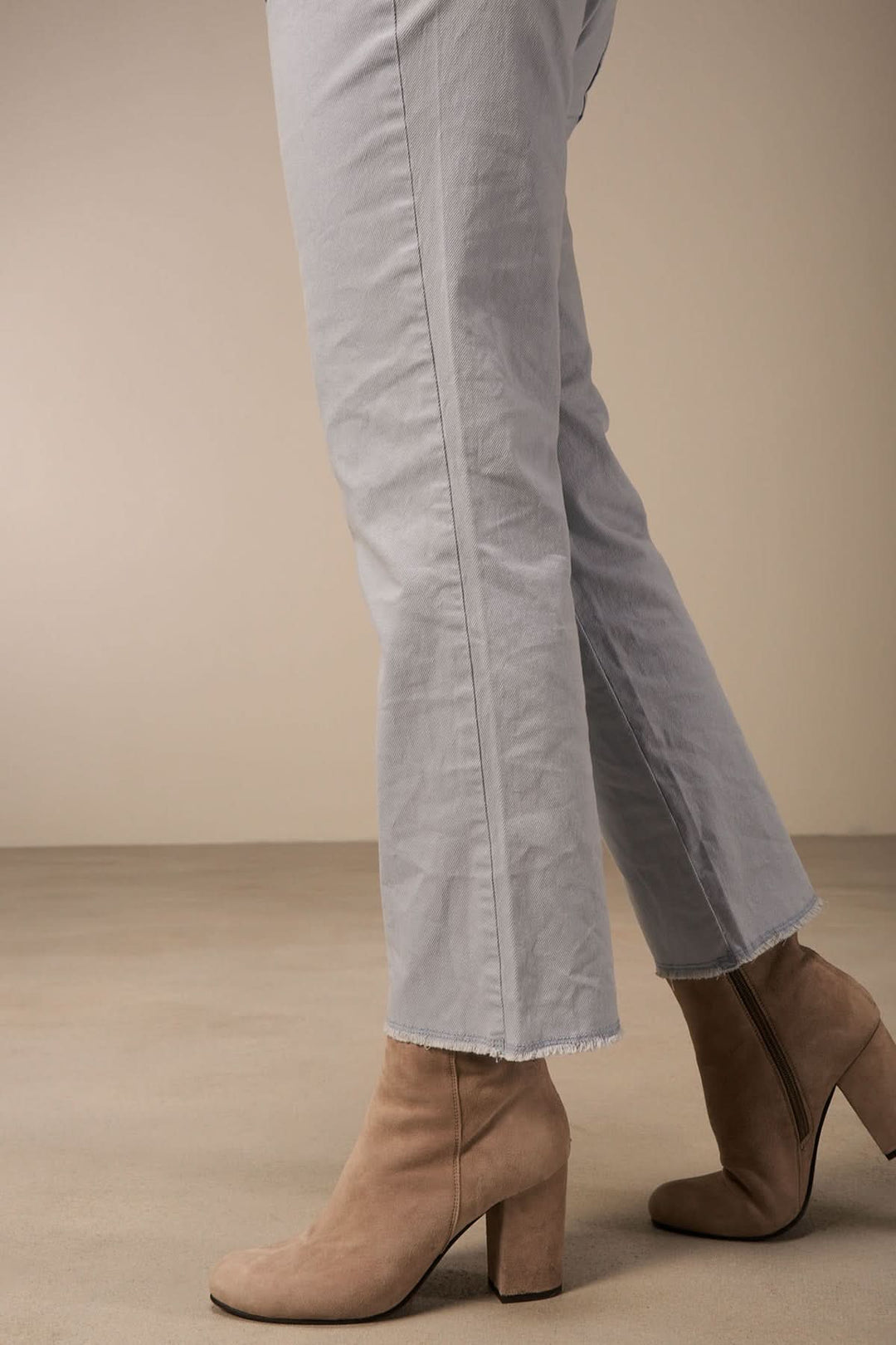 Pantalon bootcut en coton bio avec bordure à franges, porté avec des bottines élégantes.