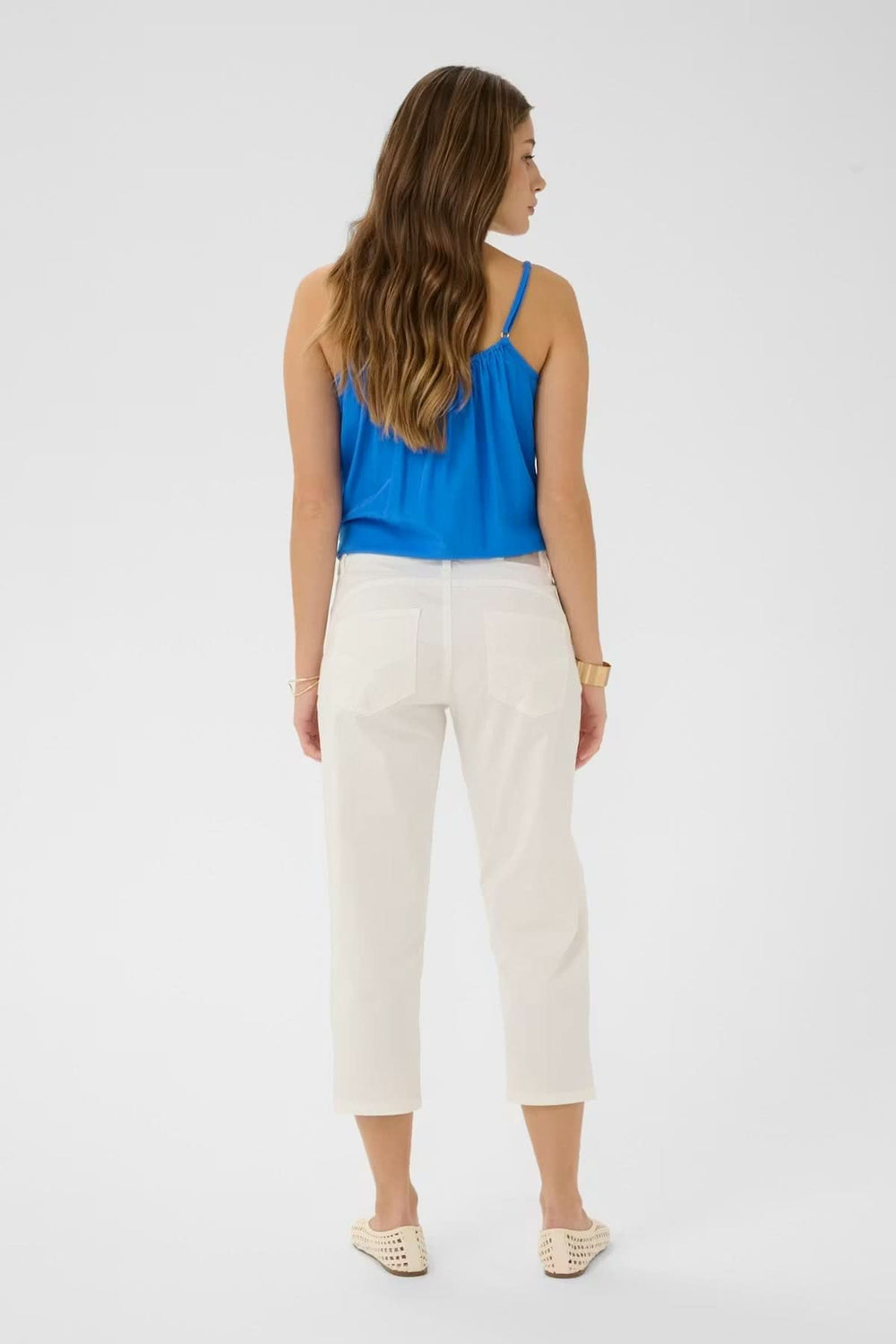 Pantalon capri Berta coupe droite vu de dos, longueur mi-mollet, porté avec un haut bleu et des chaussures décontractées.