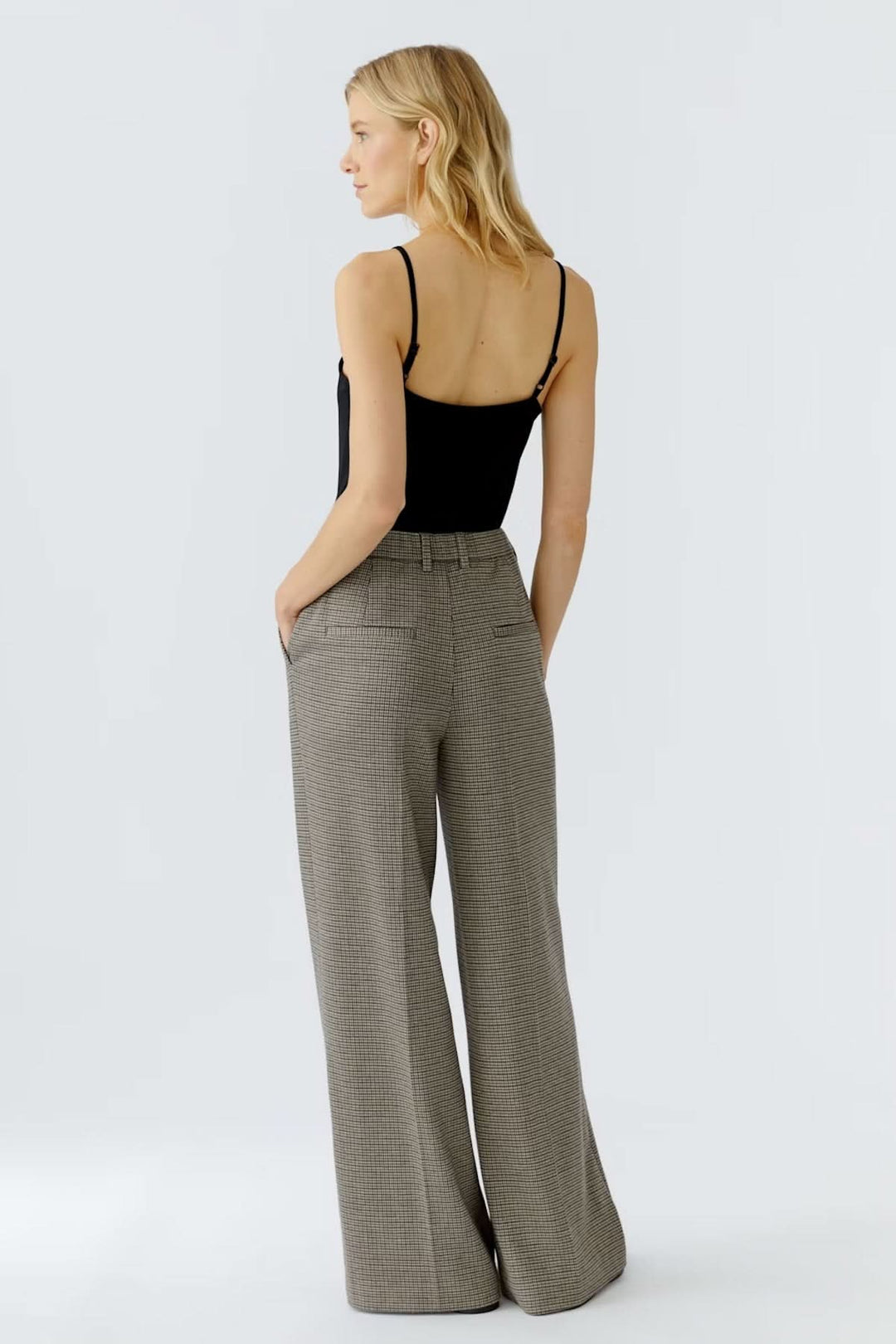 Femme portant un pantalon à carreaux ample et fluide, taille régulière avec plis français, offrant un look professionnel.