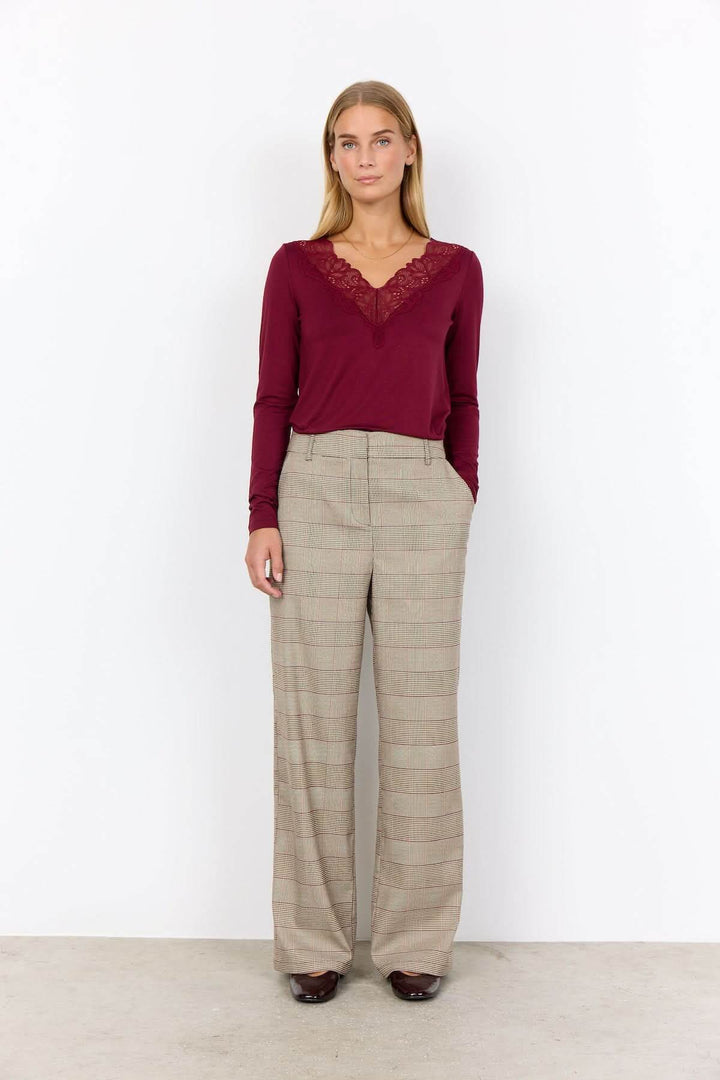 Pantalon à carreaux en coupe large avec motif prince-de-galles pour un look classique et moderne, porté avec un haut élégant.