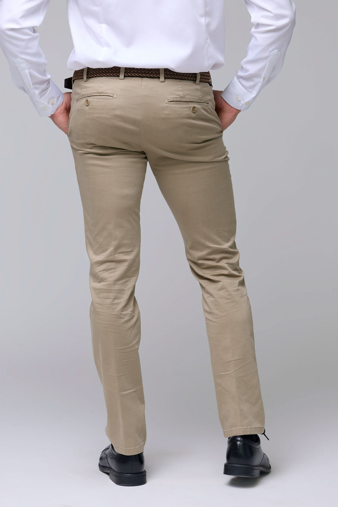 Homme portant un pantalon chino ajusté beige avec une coupe moderne et des poches arrière pour un look professionnel et décontracté.