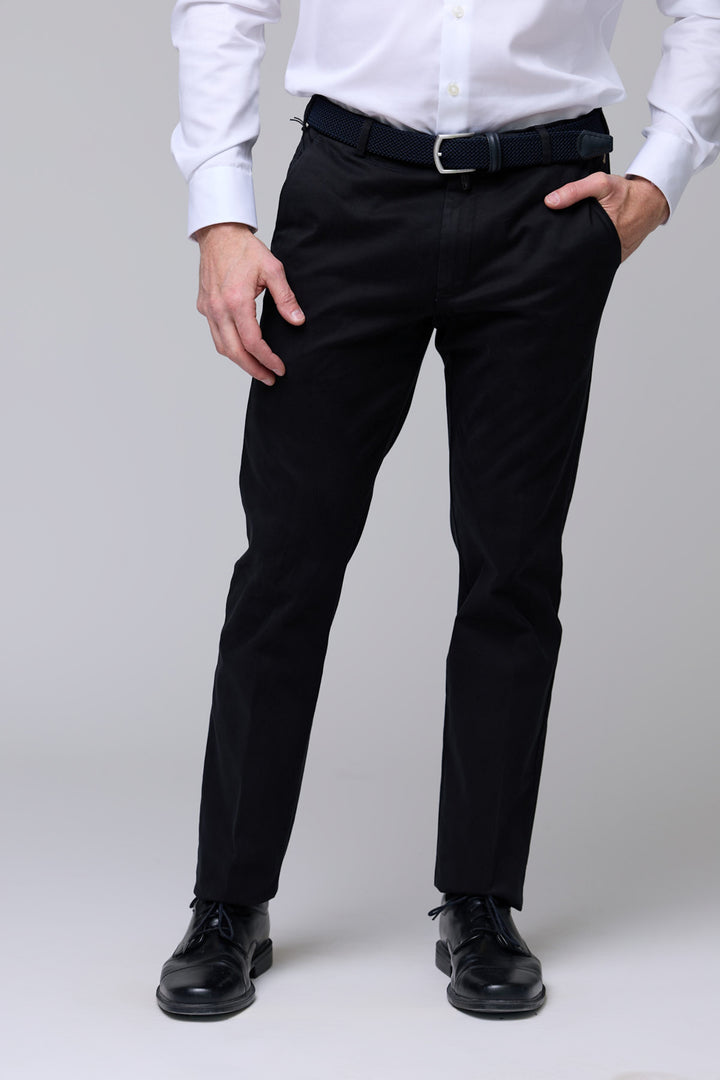 Homme portant un pantalon chino ajusté noir avec ceinture et chemise blanche, élégant et moderne, pour un look professionnel et décontracté.