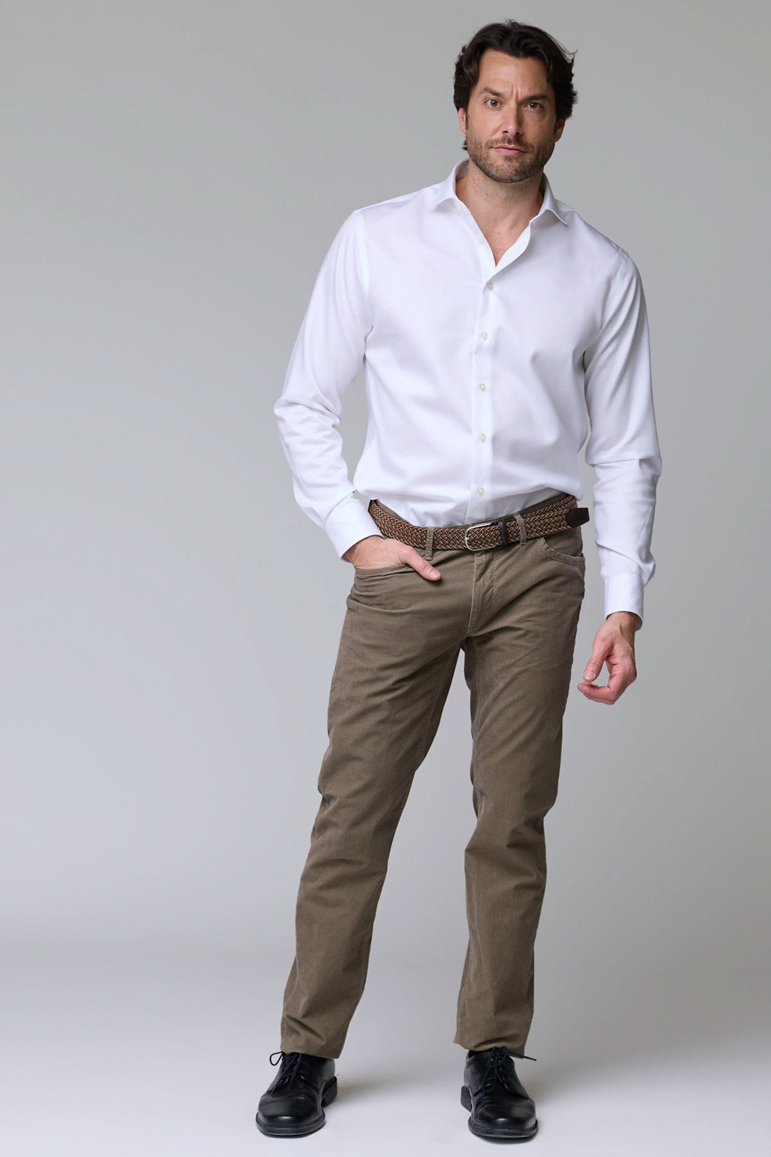 Homme portant un pantalon cinq poches en velours côtelé avec chemise blanche, alliant élégance et confort pour un style polyvalent.