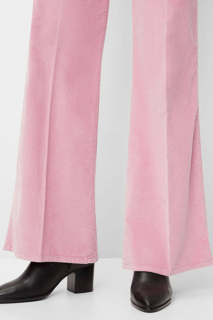 Pantalon corduroy Maine rose avec coupe évasée et élégante, porté avec des bottines noires.