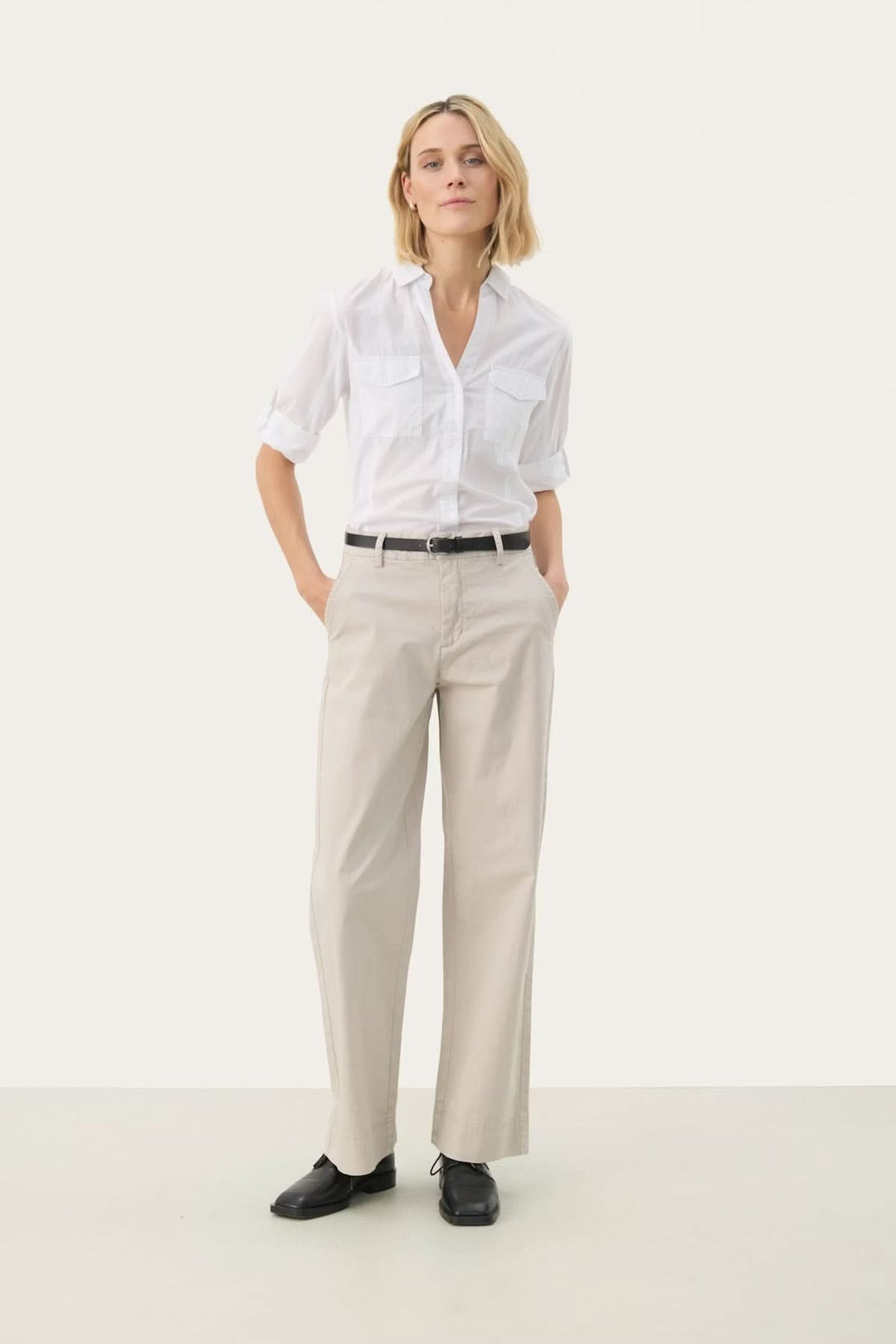 Femme portant un Pantalon à coupe droite beige avec une chemise blanche, alliant confort et élégance, idéal pour le bureau ou des sorties décontractées.