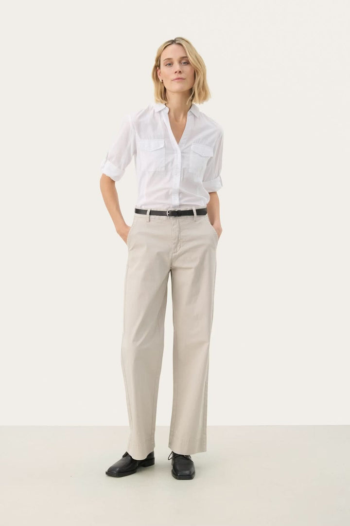 Femme portant un Pantalon à coupe droite beige avec une chemise blanche, alliant confort et élégance, idéal pour le bureau ou des sorties décontractées.