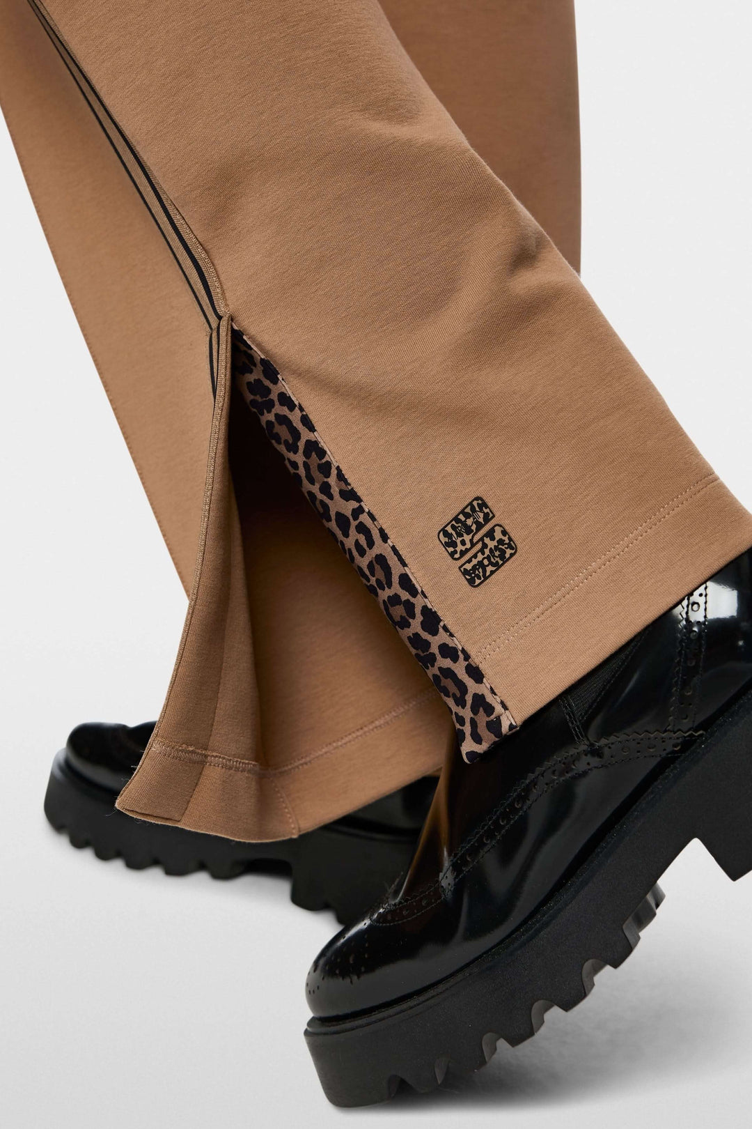 Pantalon décontracté à bandes contrastantes avec détails élégants et semelle de chaussure noire.