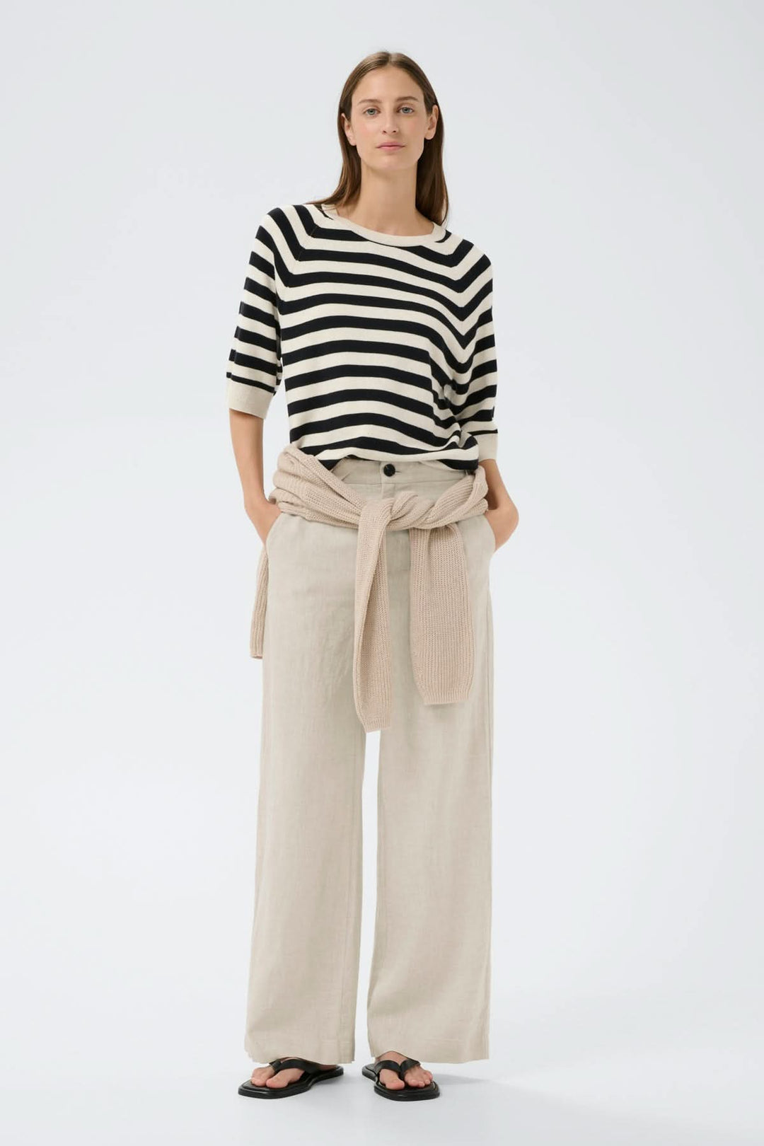 Femme portant le pantalon de lin Solina avec une taille haute et jambes larges, style élégant et décontracté.