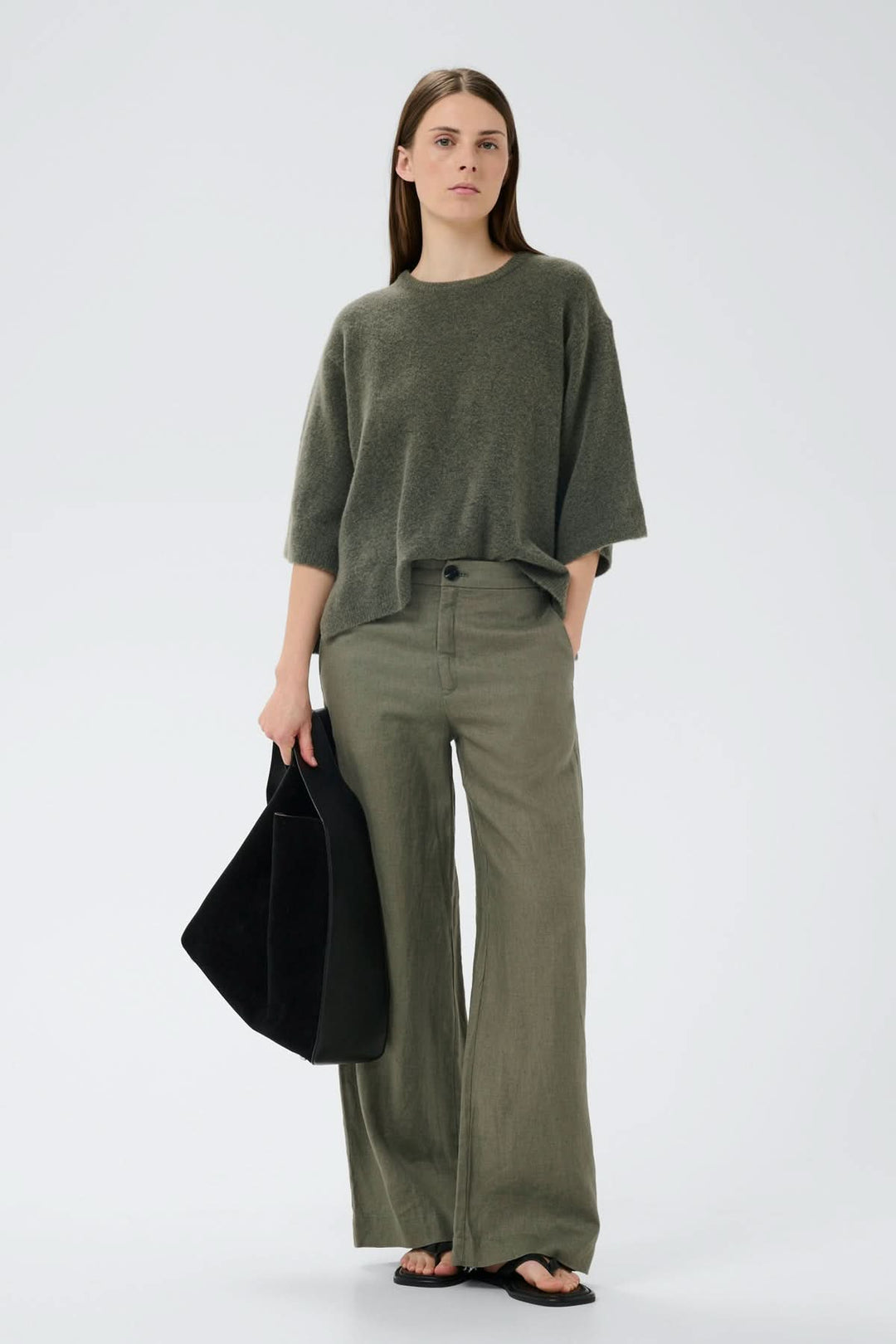 Femme portant le Pantalon de lin Solina avec un design classique, jambes larges, taille haute et poches. Look décontracté.